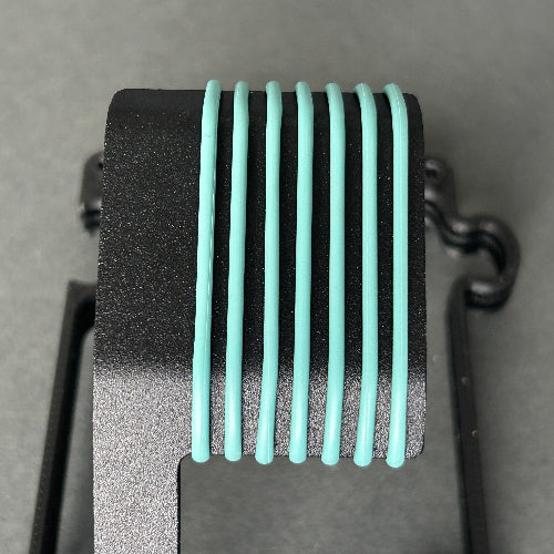A close-up of a black textured component with eight vertical mint green ribbed bars, set against a neutral gray background.