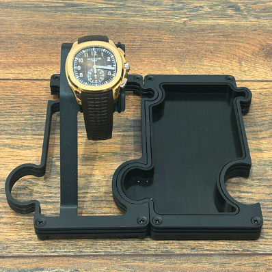 Gold watch on a black stand against a wooden background