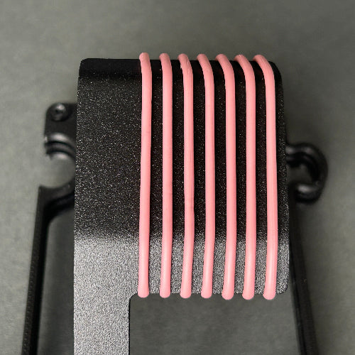 A close-up of a black metal heat sink with eight parallel pink cooling tubes attached to its fins, set against a dark gray background.