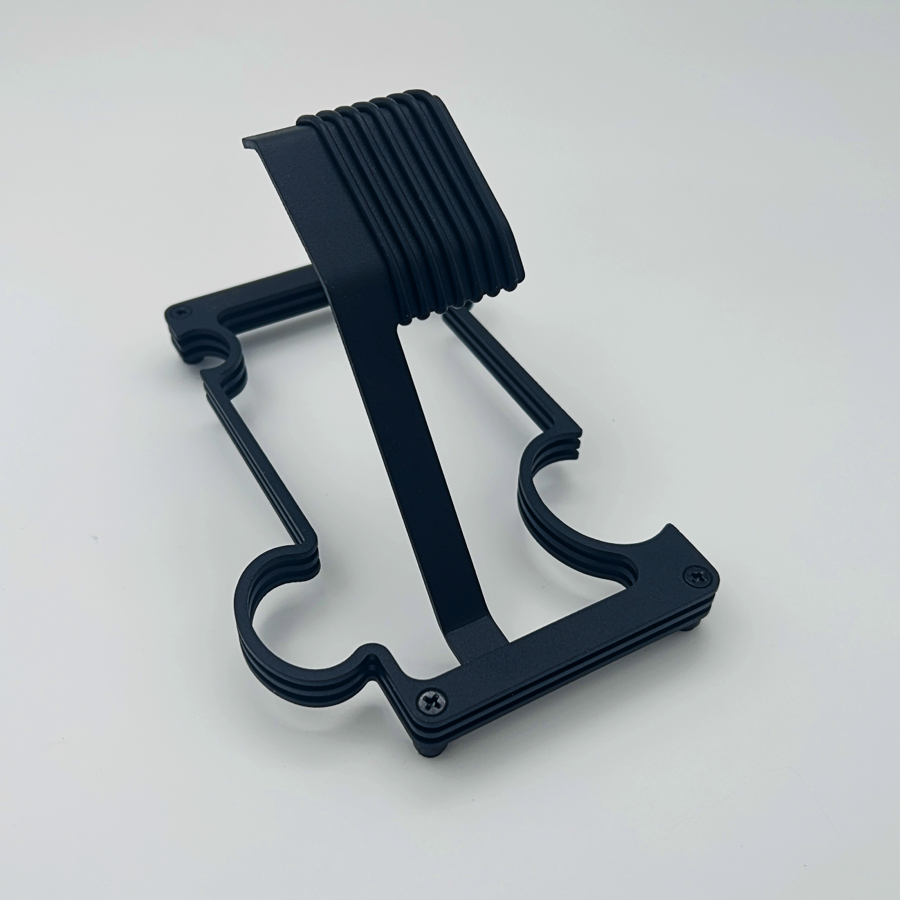 Black layered metal watch stand on white background styled like a jigsaw puzzle piece