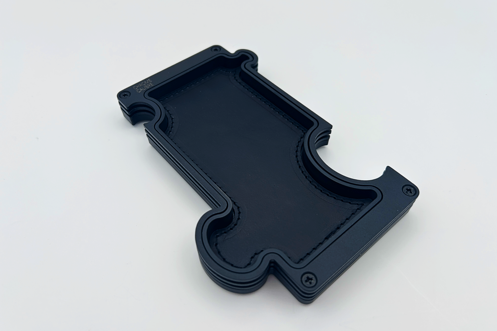 Black metal layer vanity tray with black leather inlay. shaped like a jigsaw puzzle piece