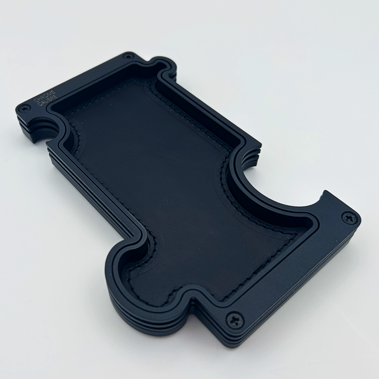 Black metal layer vanity tray with black leather inlay. shaped like a jigsaw puzzle piece