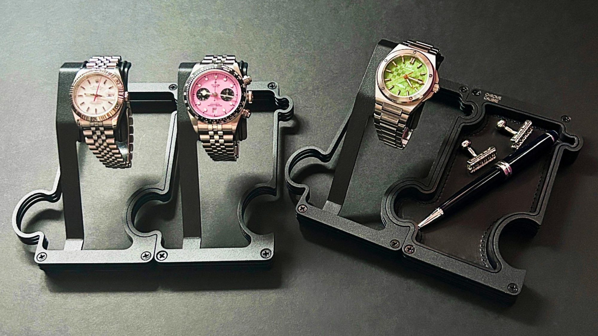 Three watches on display stands against a dark background