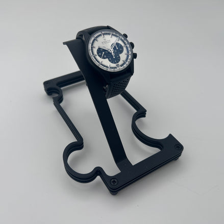 black metal watch stand with black watch on white background
