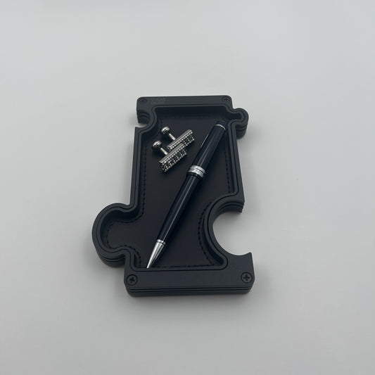 Black vanity tray with pen and cufflinks on white background