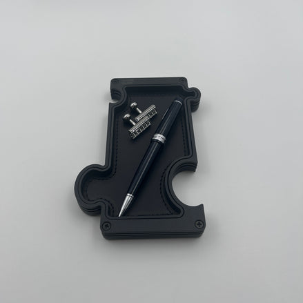 Black vanity tray with pen and cufflinks on white background