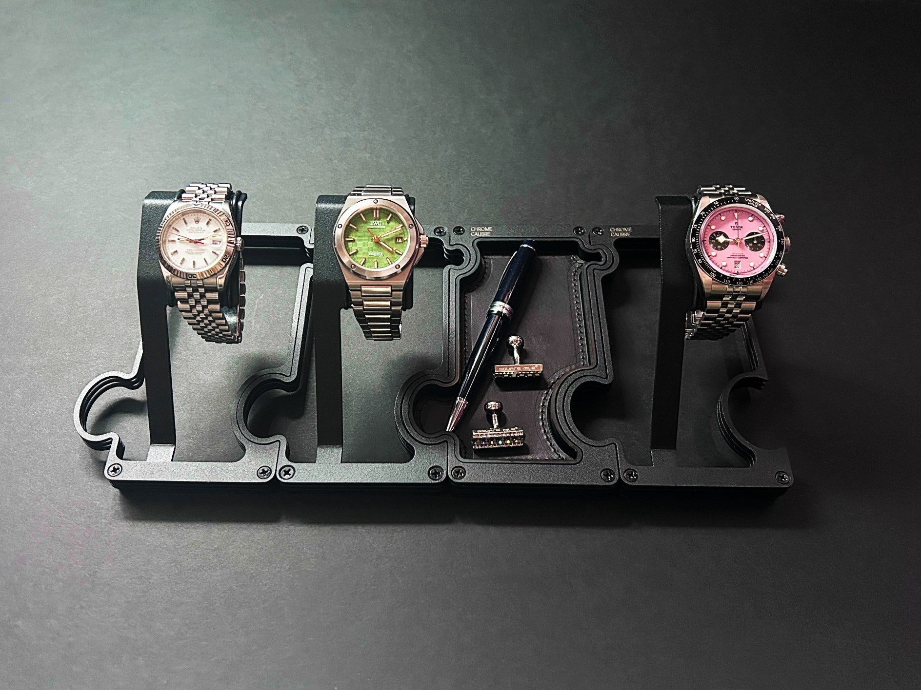 three watches on a display stand against a dark background